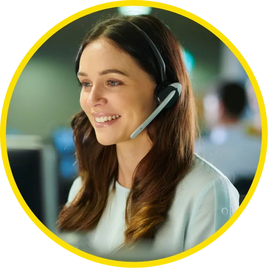 Smiling customer service representative wearing a headset and working at a computer