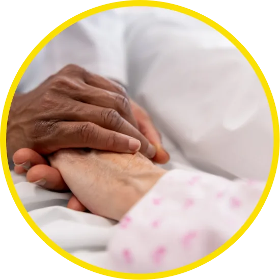Close-up of one person gently holding another's hand in a hospital or care setting